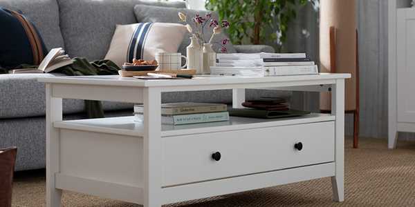 A white coffee table with storage space displayed in a living room with grey sofa.